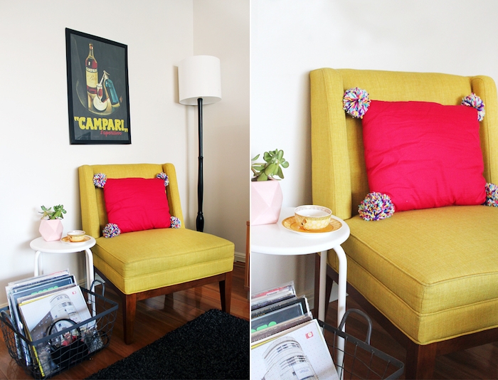 diy déco chambre avec un coussin rouge décoré de pompons colorés sur un fauteuil jaune, parquet marron, tapis noir, affiche decoratif