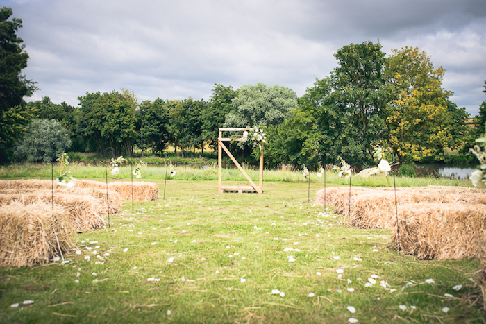 décor mariage champetre chic sur une pelouse, des meules de foin en guise d assises, arche en bois fleurie