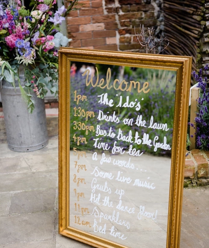 programme mariage écrit sur un miroir au feutre doré et blanc, decoration bouquet champetre dans un pot à lair