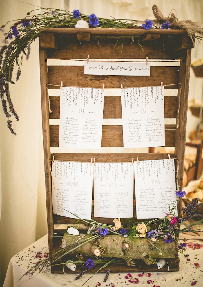 cagette bois décoration champêtre, buche de bois et fleurs champetre, listes blanches avec les noms des invités