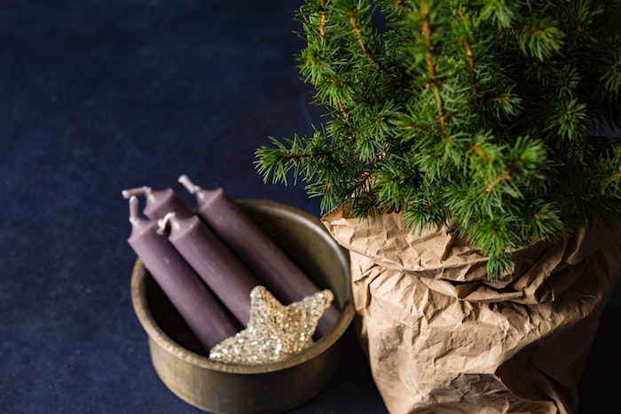 fonds d écran noel en branches vertes de pin dans un sac en papier kraft, bougies violettes et étoile dorée dans un bol gris