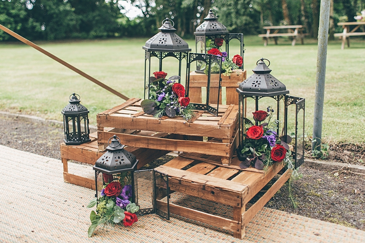 lanternes noires en metal avec des fleurs dedans, rangées autour de cagettes en bois, bouquet champetre de roses