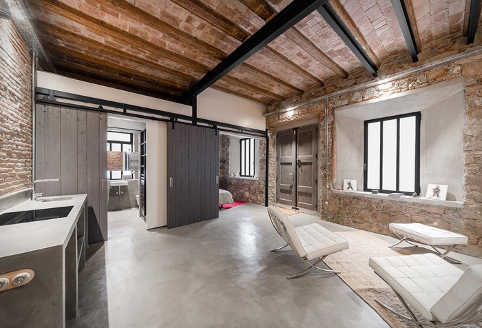 déco style loft industriel avec plancher en béton et plafond en briques et poutres bois, meubles de salon en blanc