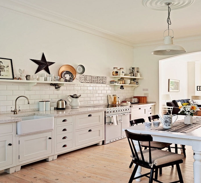 cuisine americaine avec façade blanche et carrege blanc, etageres ouvertes rangement vaisselle vintage, parquet clair, table et chaises en bois, canapé gris
