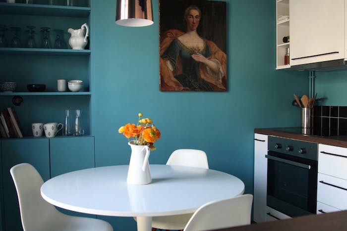 modele de cuisine ouverte sur salle à manger, façade, table et chaises blanches, mur peinture bleu pétrole