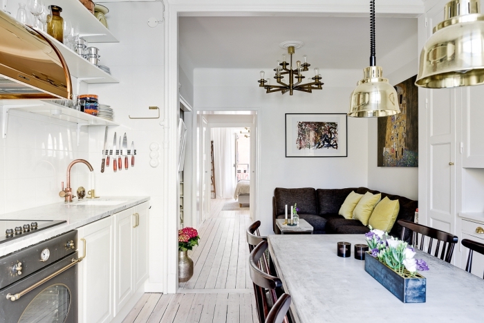 deco nordique, canapé d'angle en noir avec coussins jaune pastel, cuisine ouverte vers le salon avec salle à manger