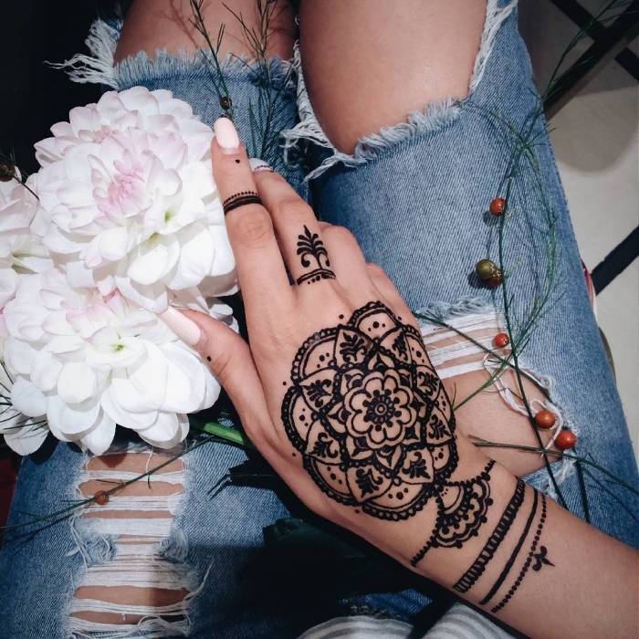 henné noir, manucure aux ongles longs et vernis blancs, modèle de tatouage au henné sur le doigt et la main