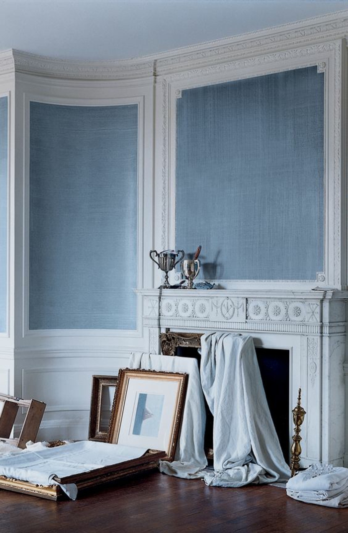 couleur bleu gris sur les murs d'une pièce en style classique en blanc et gris avec grande cheminée blanche et des grands tableax 