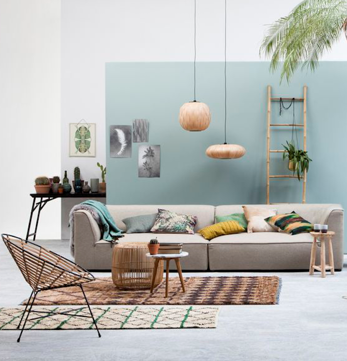 pan de mur repeint en bleu celadon et reste des murs blancs, canapé gris, tapis marron, chaise design, coussins décoratifs coloré, echelle bambou décorative