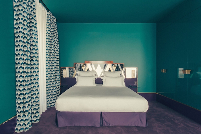 peinture bleu pétrole pour repeindre les murs d une chambre, linge de lit blanc et violet et tapis couleur violette, rideau blanc, gris et vert à motifs géométriques