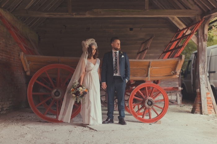 deoc champetre, une charette en bois comme fond pour une photo de couple mariés, femme en robe champetre blanche