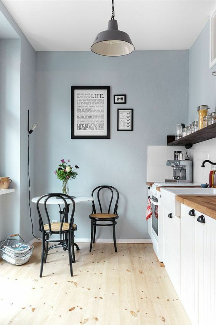repeindre sa cuisine en bleu pastel, quelle couleur pour les murs d'une cuisine, luminaire gris foncé en style industriel, deux chaises de bistrot noires, en style rétro, avec des dossiers, sol revêtu de parquet lisse en PVC, en couleur beige, avec des petites taches marron