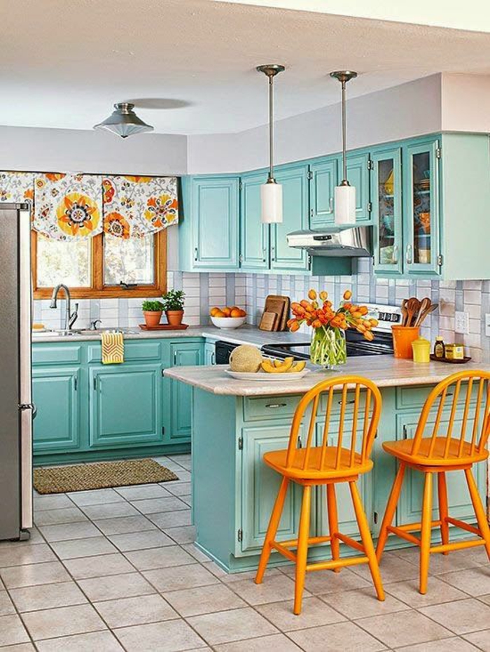 peinture pour meuble de cuisine en bleu pastel, avec carrelage carré en rose poudré, chaises de bistrot colorées en orange, luminaires blancs suspendus, en forme de tube