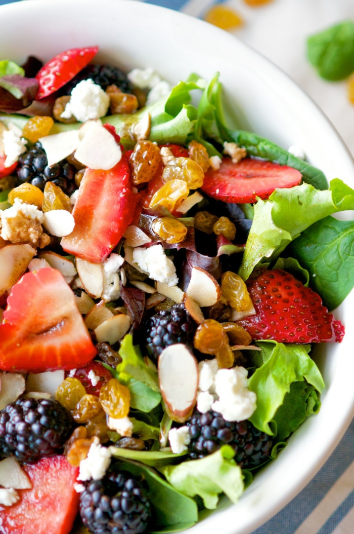 salade composée d'été, salade riche en vitamines avec des raisins secs, des fraises, du fromage émietté