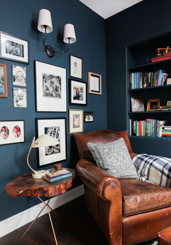 deco salon bleu canard angle de repos et de lecture avec une niche avec des étagères avec des beaucoup de livres et beaucoup de tableaux sur l'autre grand mur en couleur bleu gris