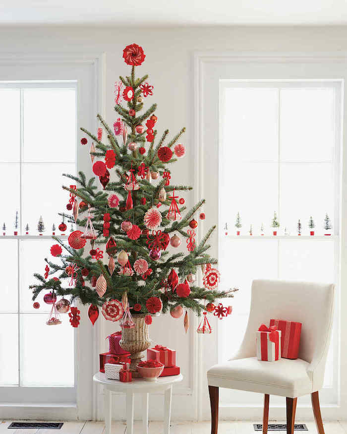 sapin de noel décoré d ornements rouges et blancs, chaise blanche, parquet et murs blancs, design épuré
