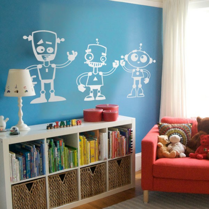 stickers chambre bébé avec trois robots blancs sur fond de mur en bleu canard au dessus d un meuble de rangement en blanc a côté d'un fauteuil rouge