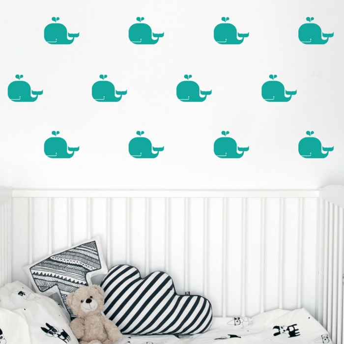 stickers chambre fille aux motifs baleines en bleu canard sur fond de mur blanc au dessus d un lit avec des peluches et des coussins en forme de nuage et en forme de la lettre T