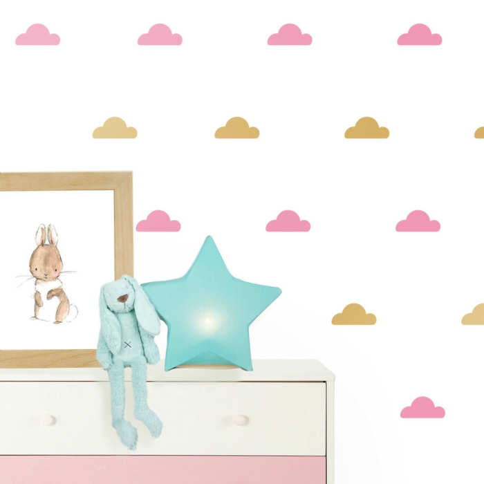 stickers chambre fille avec des nuages en rose et beige doré sur fond de mur blanc avec lapin en bleu canard et étoile en peluche en bleu canard posés sur la commode en blanc et rose