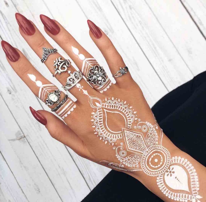 henné blanc, tatouage temporaire sur les doigts et la main, manucure aux ongles longs et vernis rouge