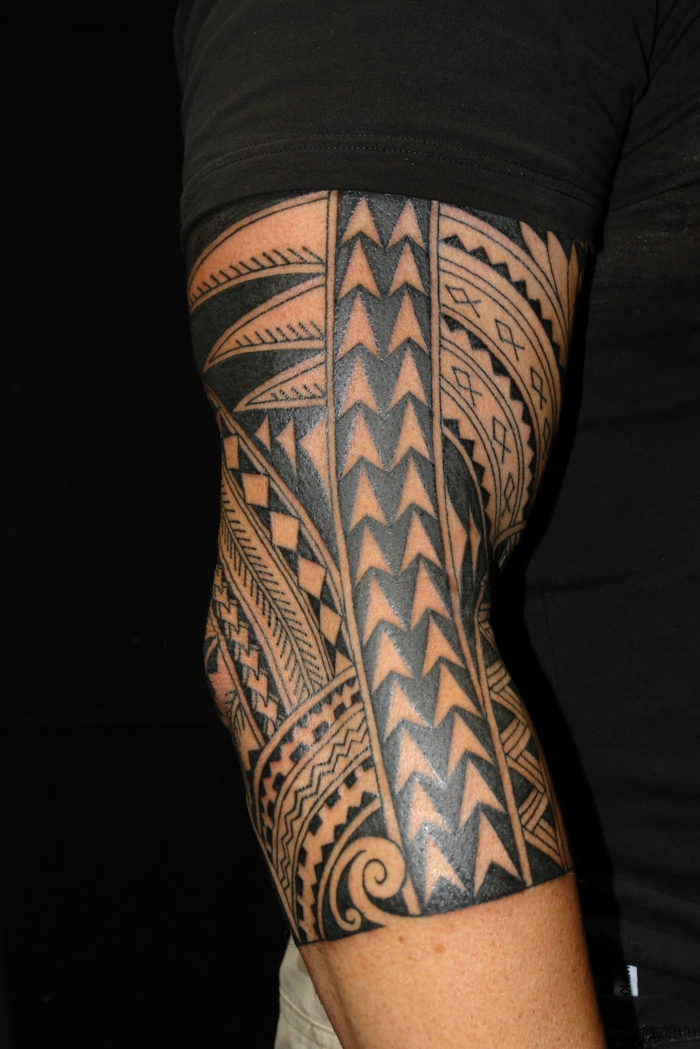 tatouage maorie homme, figures ethniques tatouées sur un bras masculin