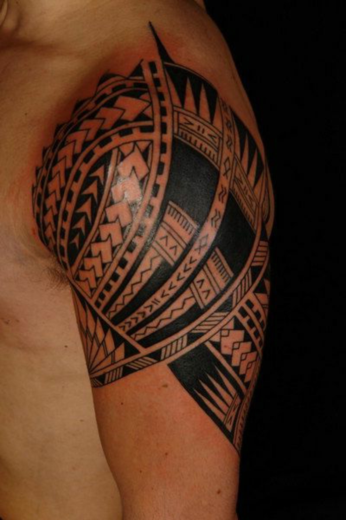 tatouage noir, symboles maoriens tatoués au bras, bras musclé tatoué avec image ethnique