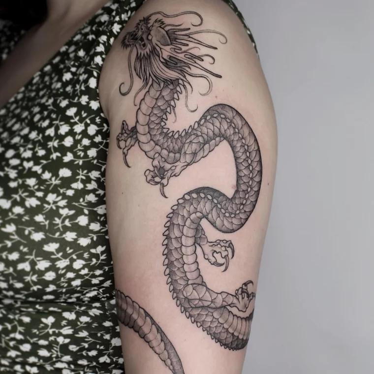 tatouage epaule bras femme dragon griffes ecailles corps serpentiforme