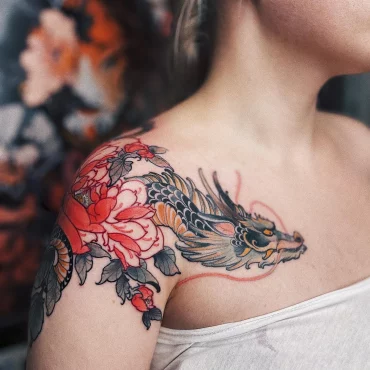 tatouage epaule poitrine femme dessin dragon creature ecailles fleur rouge