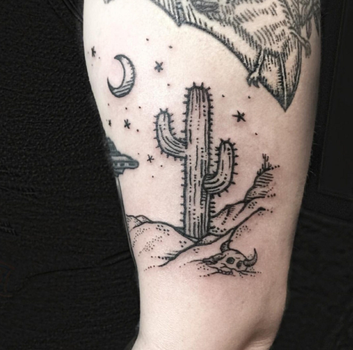 tatouage femme cuisse, paysage absurde d'un désert avec ciel étoilé, lune et grand cactus
