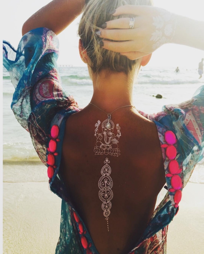tatouage temporaire, blouse bleu à motifs pompons rose pour femme, coiffure cheveux balayage, tatouage au henné blanc sur le dos