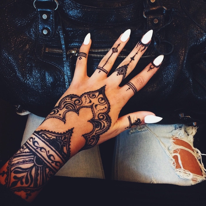 tatouage henné noir, mains féminins au vernis blanc avec dessins temporaires à design ethnique