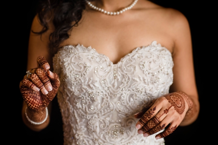 modele henné, robe de mariée blanche avec bustier en coeur et collier en perles blanches, tatouage au henné rouge sur les mains