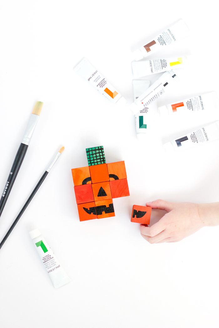 un puzzle jack o' citrouille réalisé avec des cubes en bois peints en orange et décorés au feutre noir, activite manuelle amusant et éducatif sur le thème d'halloween