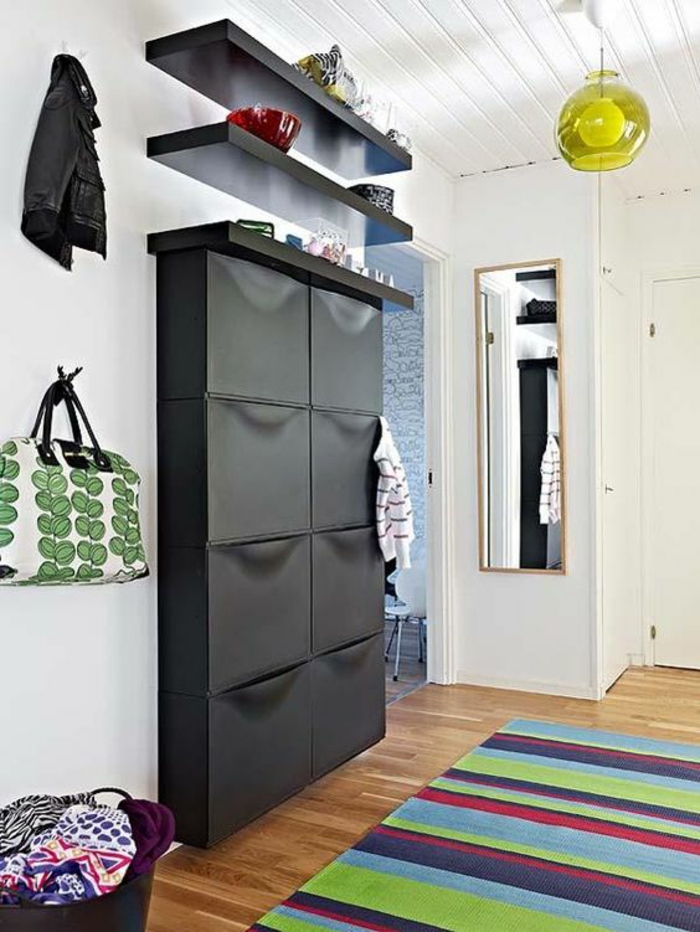 deco couloir avec plafond revêtu de bois peint en blanc, grand meuble rangement IKEA en noir, deux étagères noires, tapis en rayures horizontales en rouge, vert, bleu marine et bleu pastel