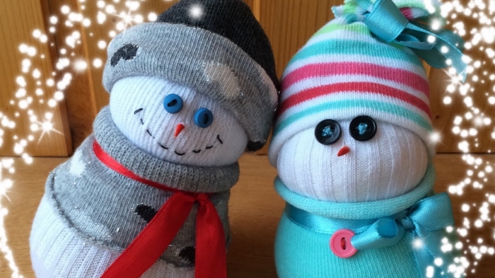 bonhomme de neige chaussette, figurine blanche habillée en gilet gris à coeurs blancs avec écharpe en ruban rouge