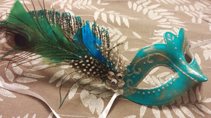masque carnaval maternelle, modèle de masque turquoise avec décoration glitter argenté et plumes de paon
