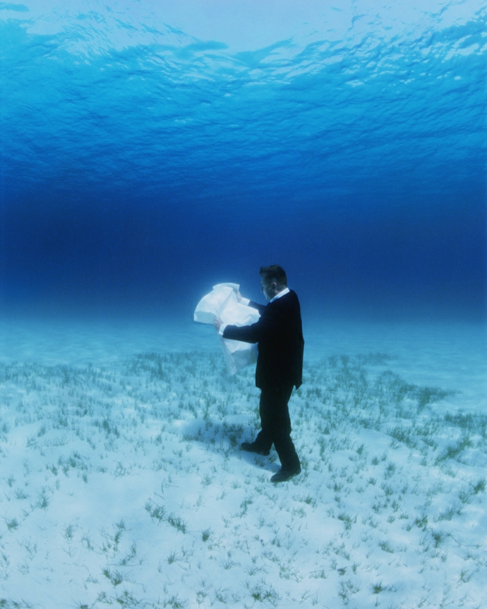 artiste contemporain Philippe Ramette, photographie, un homme qui marche, carte à la main, sur la profondeur de la mer en cherchant à l'explorer