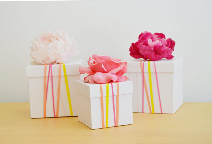 idée de voite cadeau carton décorée de bandes en papier coloré et fleurs fraiches sur le couvercle