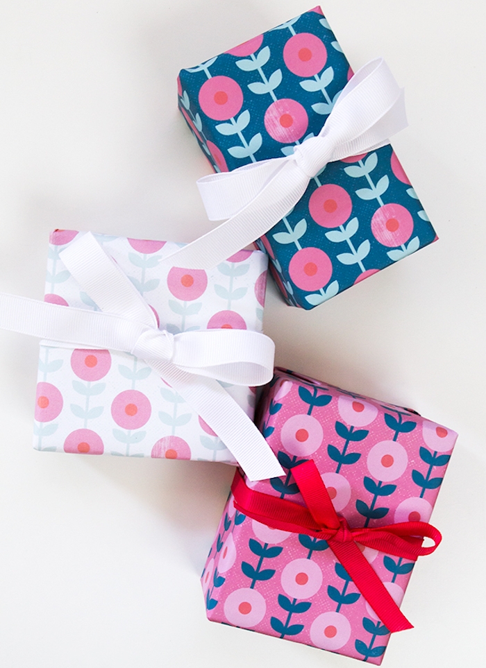 emballage cadeau simple et esthétique, papier cadeau en rose, blanc et bleu à motifs floraux, décoration de ruban blanc et rouge