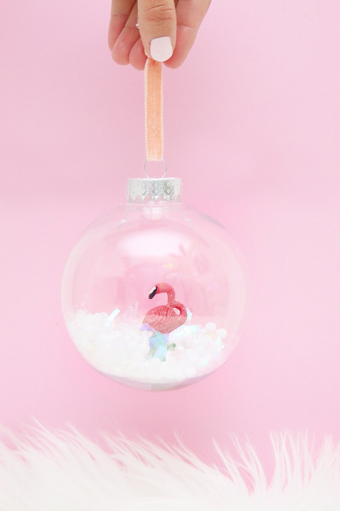 jolie idée pour une déco de noël à faire soi même facile à réaliser avec des boules de sapin transparentes, fausse neige et figurines flamant rose