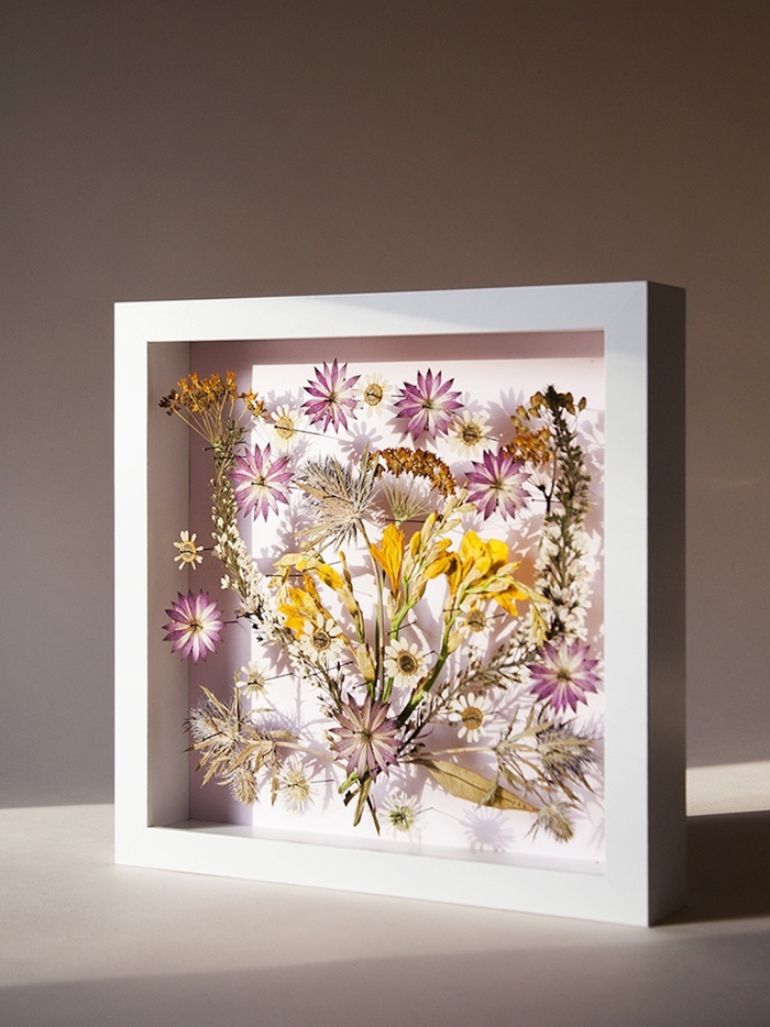 idée originale pour un activité manuelle printemps avec des fleurs pressées encadrées, joli tableau de fleurs séchées à encadrement blanc