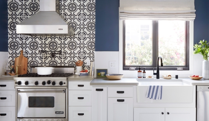 carrelage blanc, peinture murale dans la cuisine en blanc et bleu foncé, meubles de cuisine en bois peints blanc avec poignées noires
