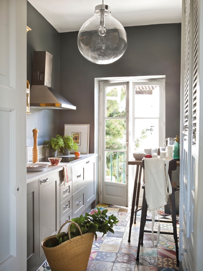 carreaux de ciment sur le sol à design géométrique et multicolore, cuisine aux murs gris foncé et meubles gris clair