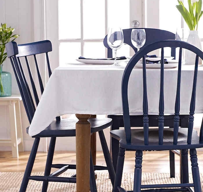 chaise relookée, exemple de chaises salle à manger repeintes e violet, table en bois, couverte de nappe blanche, tapis beige