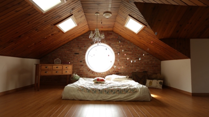 amenagement combles, chambre à coucher au grenier avec plafond en bois foncé et murs en briques rouges
