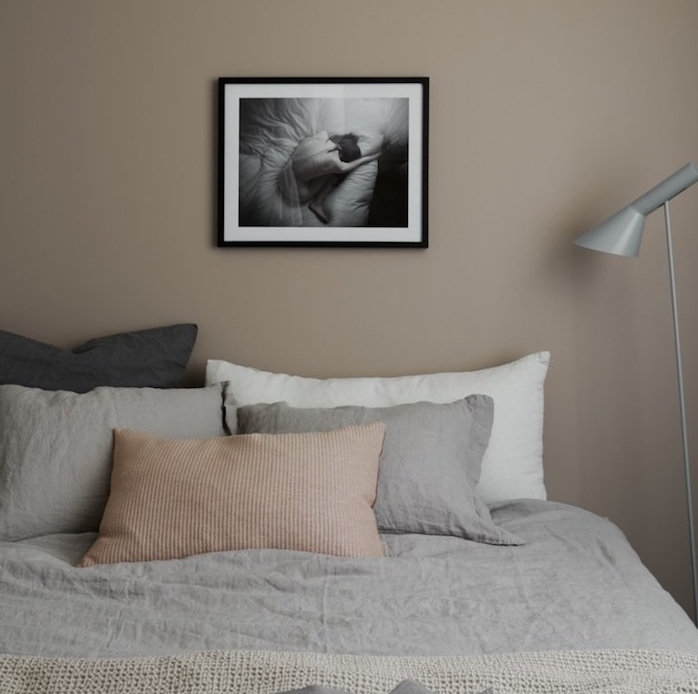 chambre à coucher couleur taupe clair, linge de lit gris, blanc et beige, mur décoré de dessin en noir et blanc, lampe grise