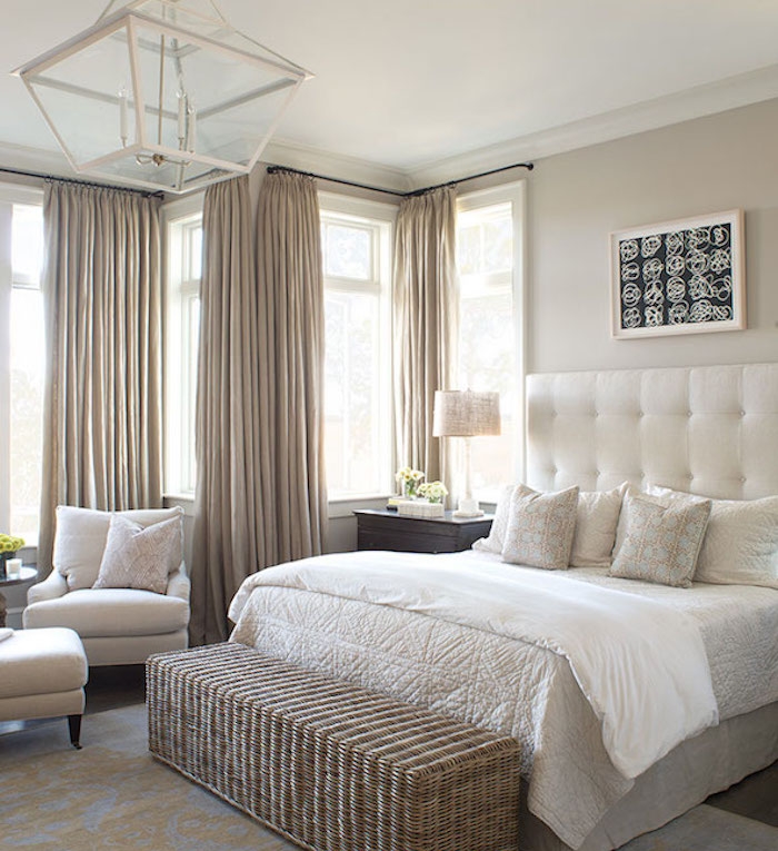 rideaux taupe couleur dans une chambre à coucher gris et blanc, bout de lit en rotin, fauteuils et linge de lit blanc et beige, lustre original