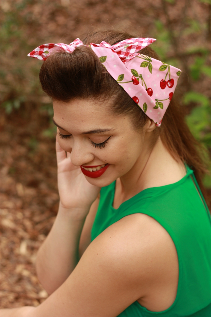 coiffure pin up avec un bandeau rose, maquillage vintage, tenue verte