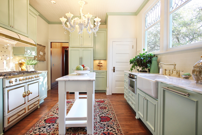 amenagement cuisine ancienne campagne en meuble cuisine vert celadon, piano de cuisson, tapis oriental, établi blanc, lustre blanc élégant
