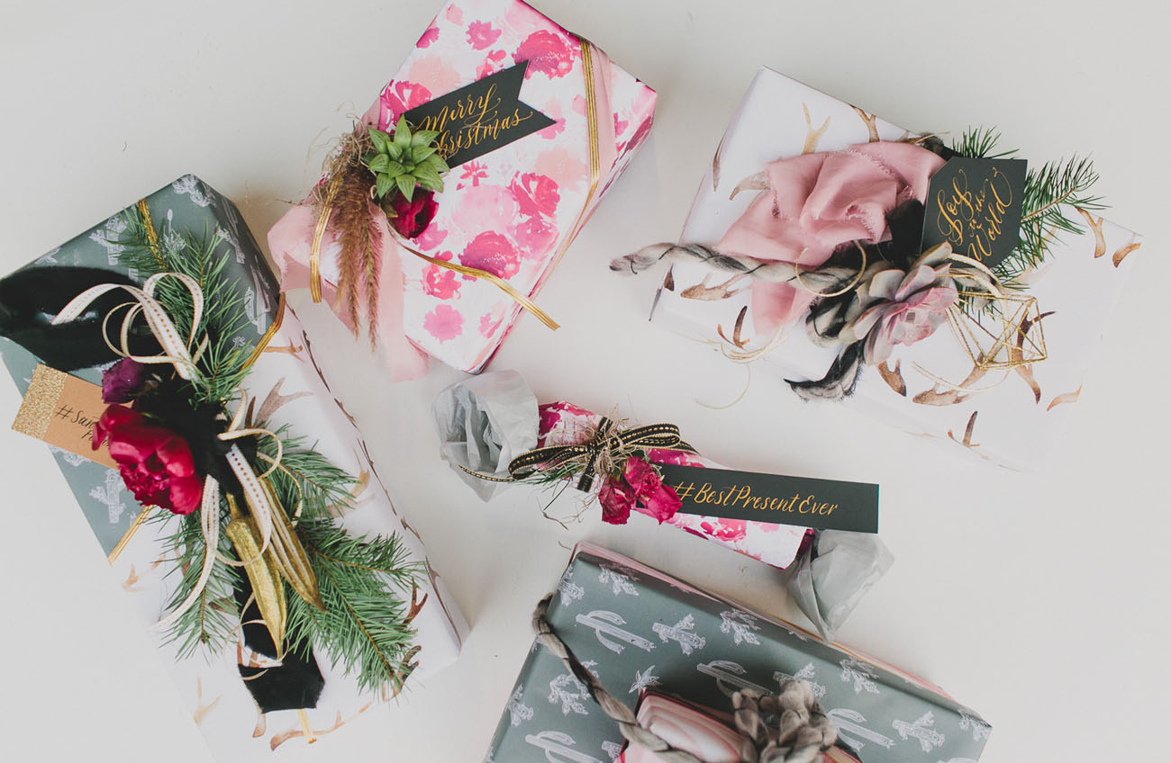 emballer cadeau en papier à motifs divers avec branches de pin, chutes de tussu et décorations naturelles de plantes et fleurs